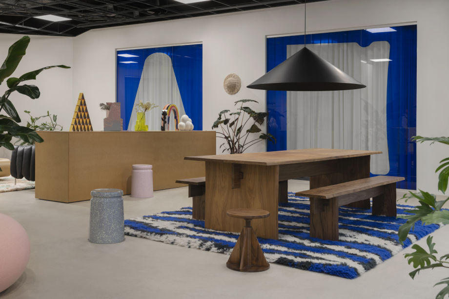 A lifestyle image from Hem's Stockholm headquarters featuring Bookmatch Table + Benches Set, Monster Rug, All Wood Stool, Last Stool, Boa Pouf, and more.