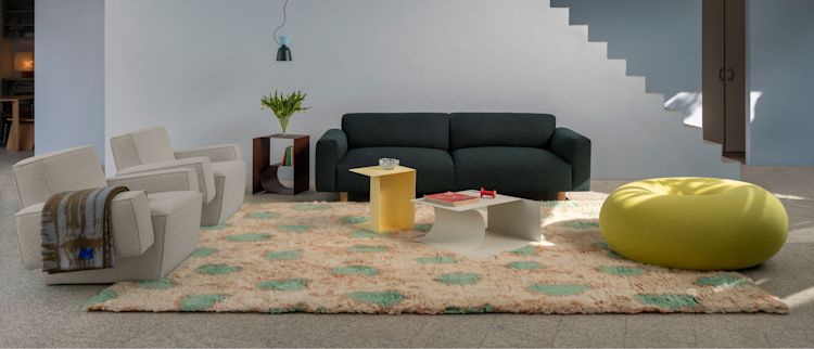 A lifestyle image of a living room scene featuring Hunk Lounge Chair with Armrests, Glitch Throw, Monster Rug, Glyph Side Tables, Alphabeta Pendant Light, Koti 3-seater Sofa, and Boa Pouf.