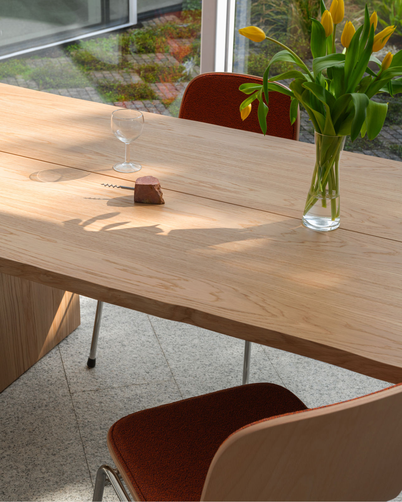 A lifestyle image of a dining scene featuring Bookmatch Table in Oak and Touchwood Chairs in Canyon / Beech / Chrome.