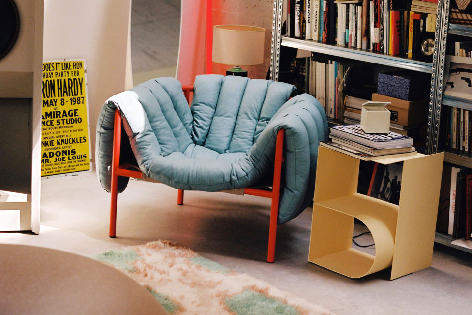 A lifestyle image of a lounge scene featuring Puffy Lounge Chair, Monster Rug, and Glyph Side Table.