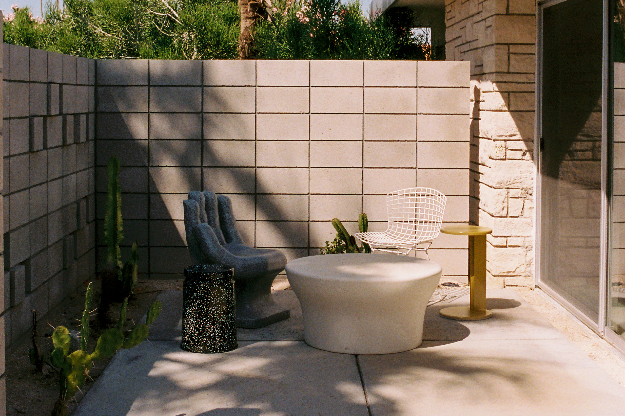 A lifestyle image of an outdoor patio scene featuring Lolly Side Table and Last Stool.