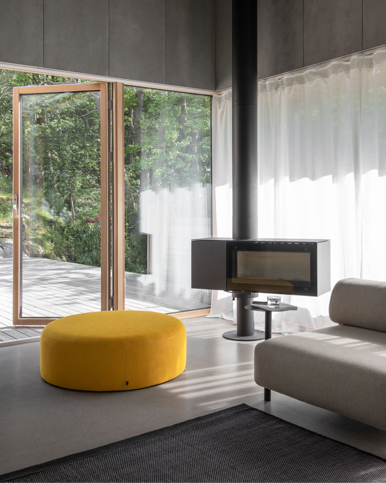 A lifestyle image of a living room scene featuring Bon Pouf Round Large, Dune Rug, and Palo Modular Sofa.