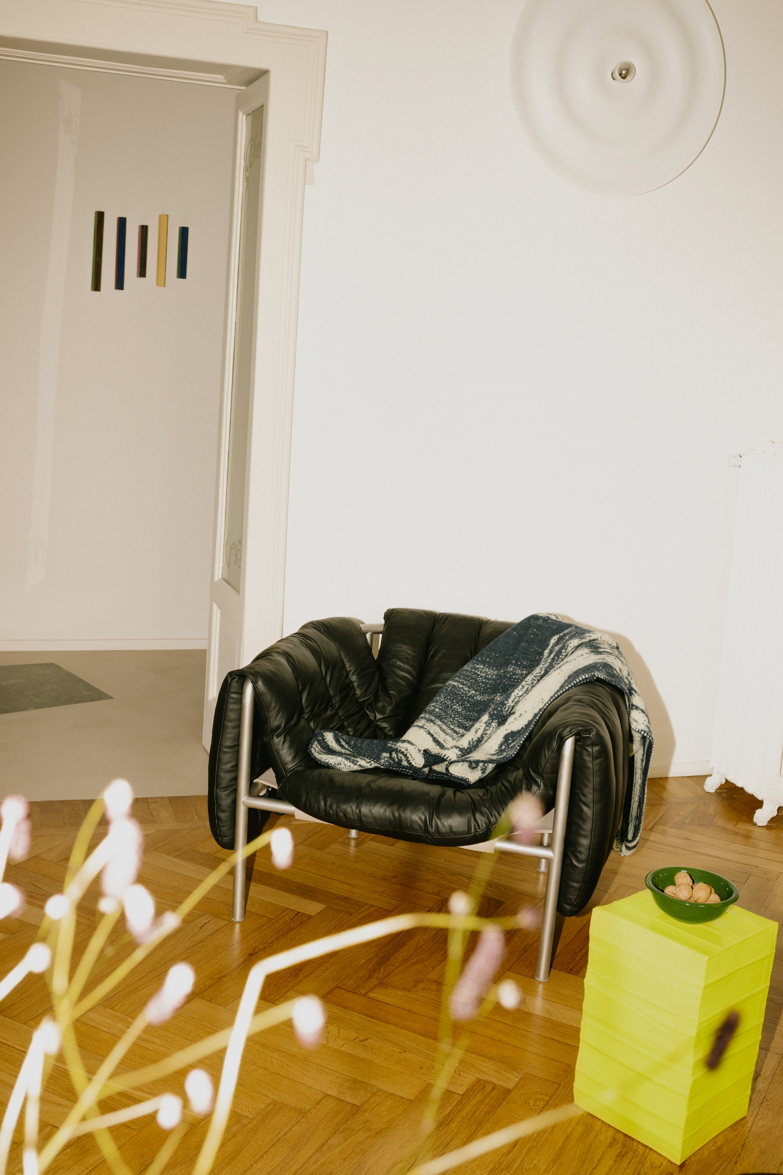 A lifestyle image of a lounge scene featuring Puffy Lounge Chair, Glitch Throw, and Bronto Bowl.