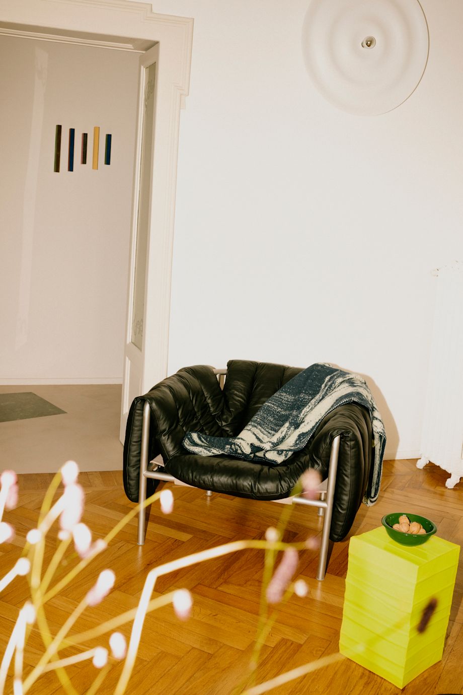 A lifestyle image of a lounge scene featuring Puffy Lounge Chair, Glitch Throw, and Bronto Bowl.