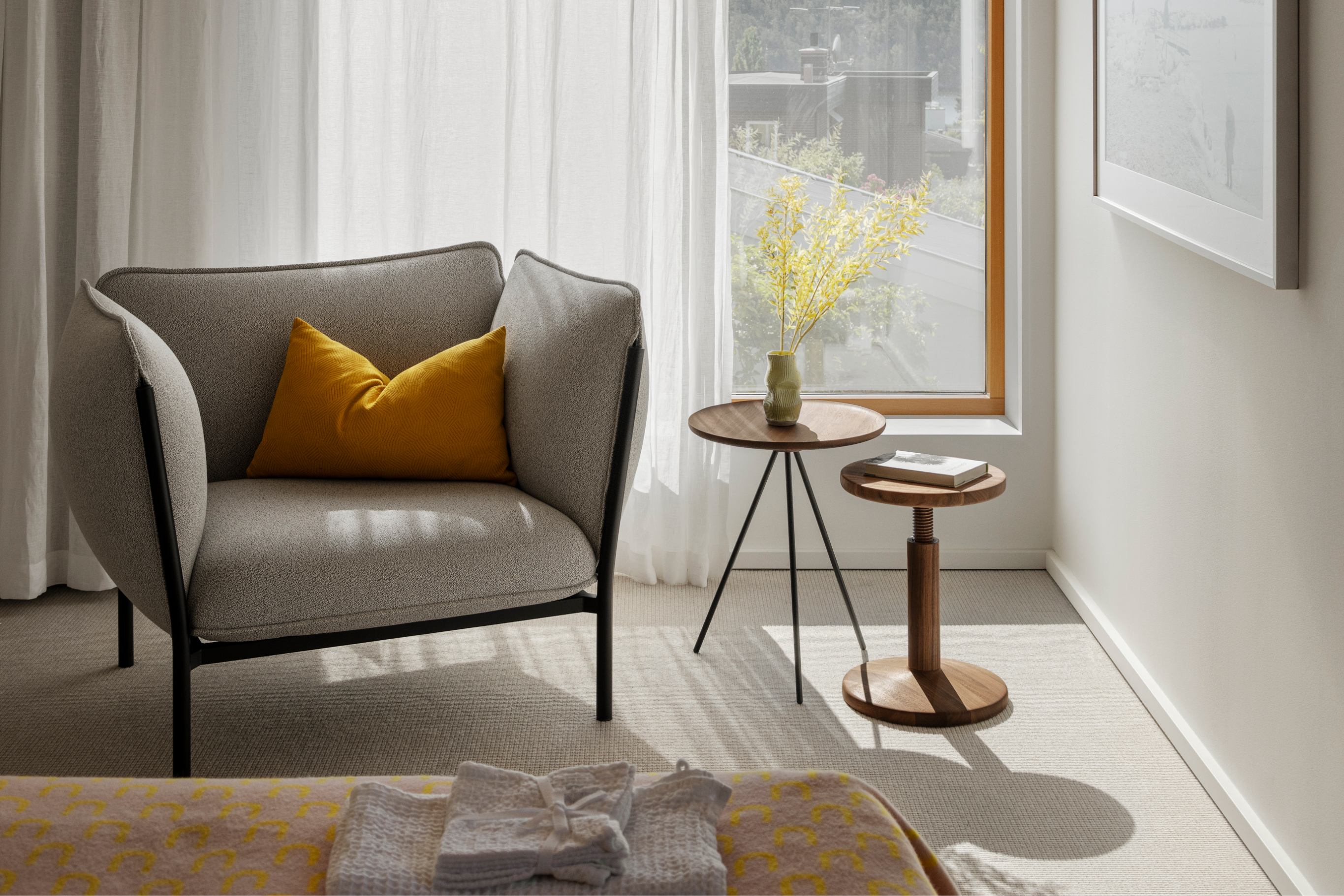 A lifestyle image of a bedroom scene featuring Kumo Modular Single Seater with Armrests, Storm Cushion Large, Key Side Table, Arch Throw and All Wood Stool.