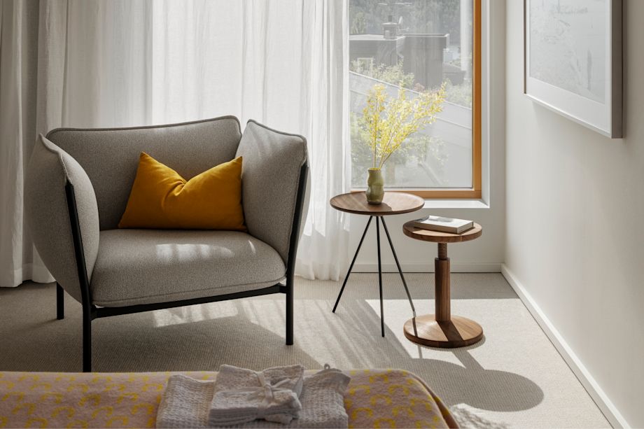 A lifestyle image of a bedroom scene featuring Kumo Modular Single Seater with Armrests, Storm Cushion Large, Key Side Table, Arch Throw and All Wood Stool.