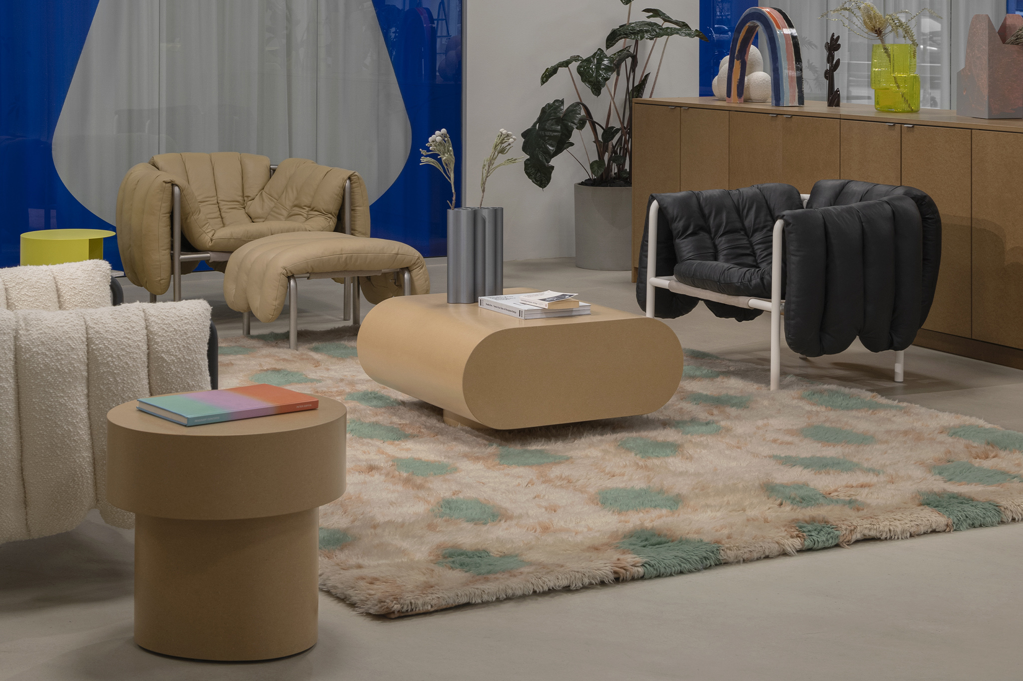 A lifestyle image from Hem's Stockholm HQ featuring Puffy Lounge Chair, Puffy Lounge Chair + Ottoman, Monster Rug, Stump Side Table, Stump Coffee Table Large, and Hide Side Table.