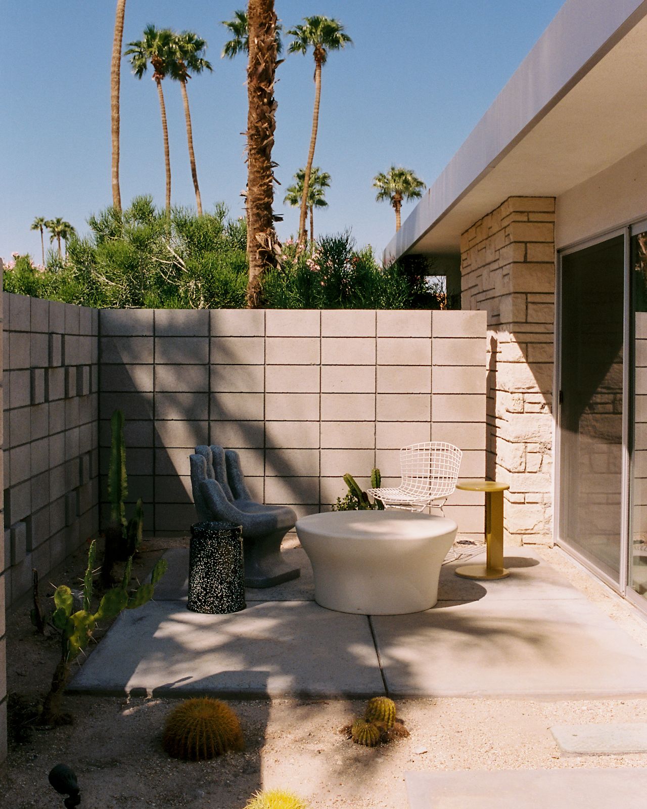 A lifestyle image of an outdoor patio scene featuring Lolly Side Table and Last Stool.