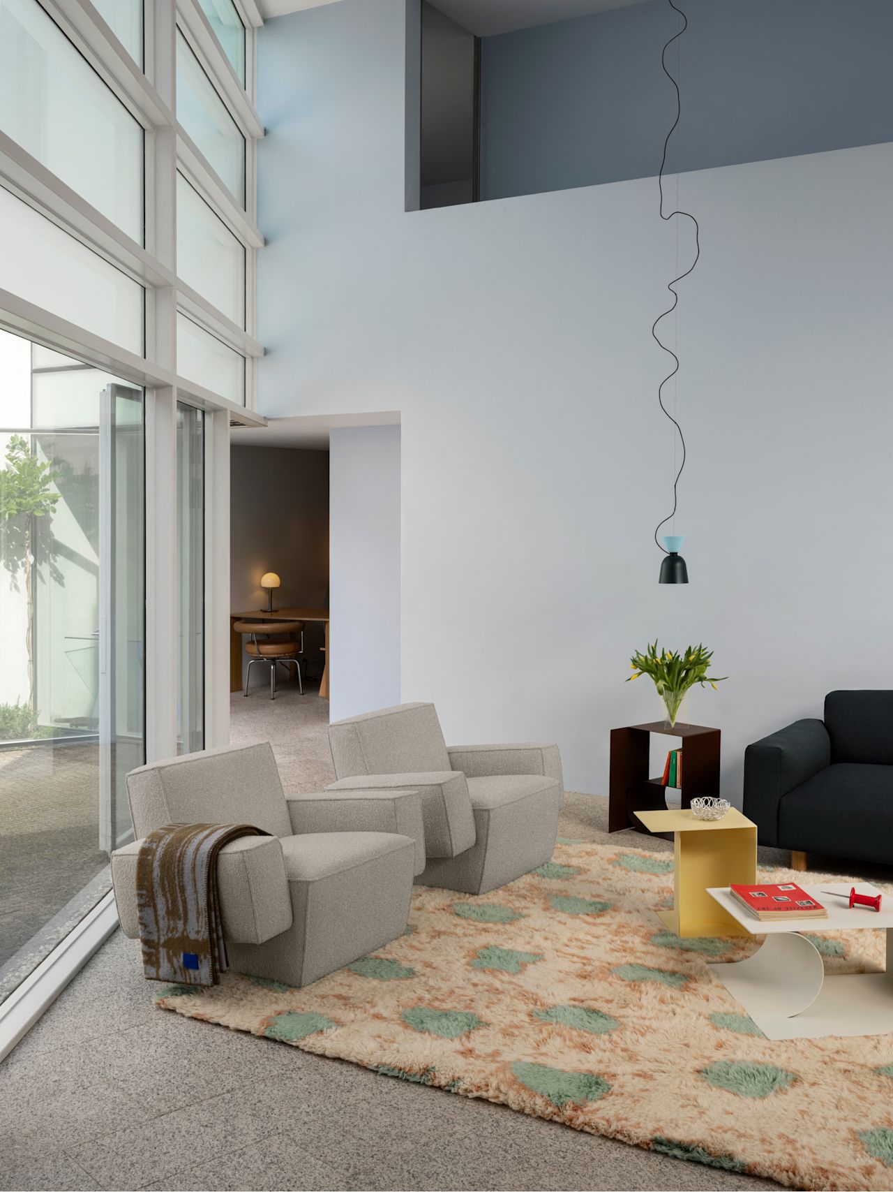 A lifestyle image of a living room scene featuring Hunk Lounge Chair, Monster Rug, Glitch Throw, Alphabeta Pendant Light, Glyph Side Tables and Koti Sofa.