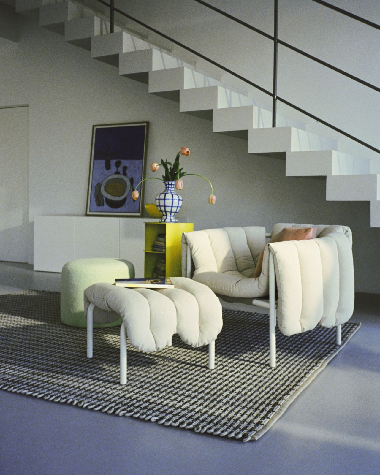 An analog image of a lounge scene featuring Rope Rug, Hide Pedestal, Bon Pouf Round, Neo Cushion, and Puffy Lounge Chair + Ottoman.