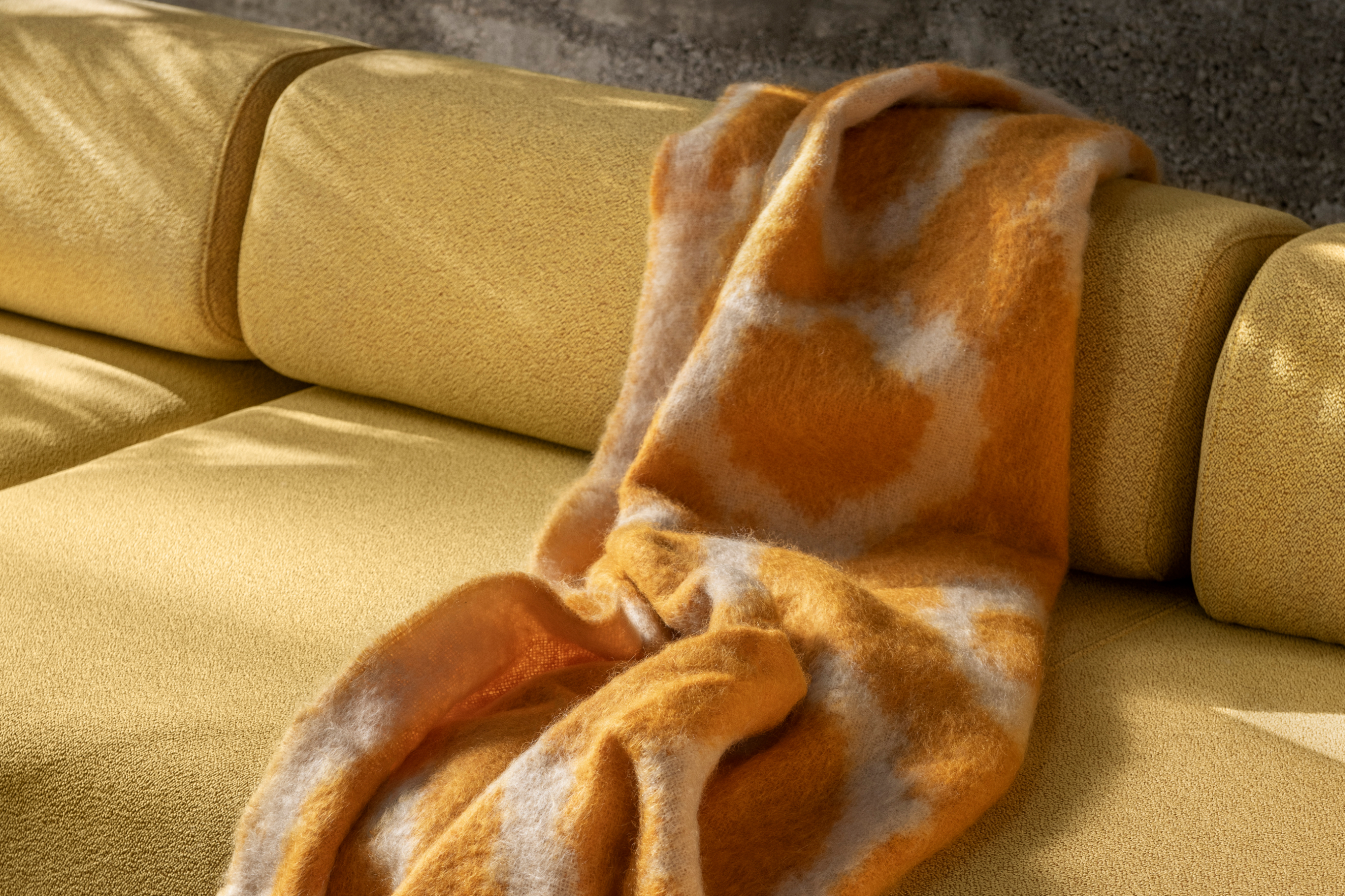 Hem - A Monster Throw in the variant Ochre / Off-White Ring draped over a Palo Corner Sofa Left in the shade Sunflower.