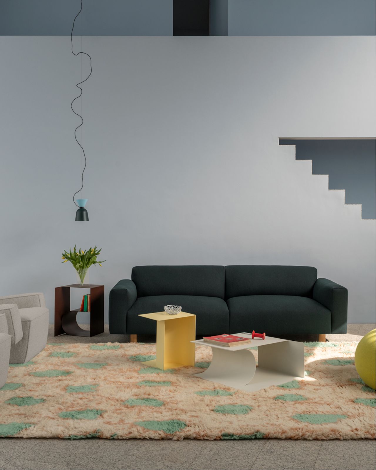 A lifestyle image of a living room scene featuring Hunk Lounge Chair with Armrests, Glitch Throw, Monster Rug, Glyph Side Tables, Alphabeta Pendant Light, Koti 3-seater Sofa, and Boa Pouf.