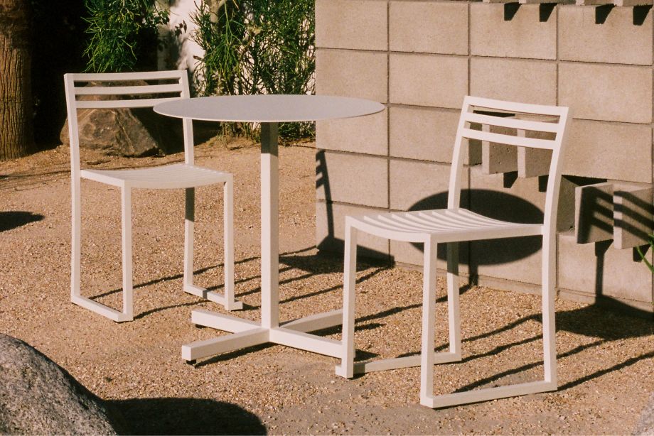 A lifestyle image of an outdoor patio scene featuring Chop Table Round and Chop Chairs (Set of 2) in Grey White.