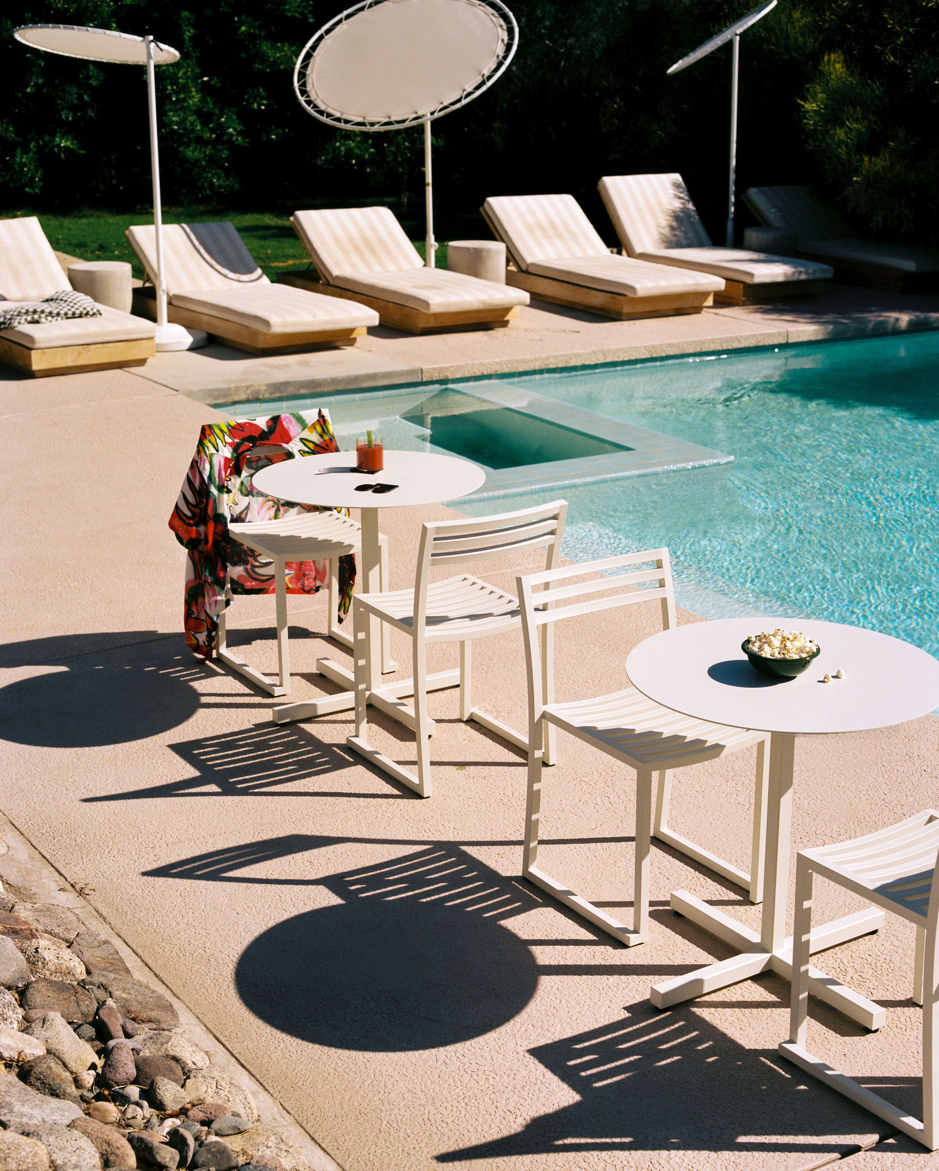 A lifestyle image of a patio scene featuring Chop Round Tables and Chop Chairs.