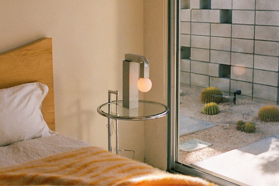 A lifestyle image of a bedroom scene featuring Monster Throw and Knuckle Table Lamp.