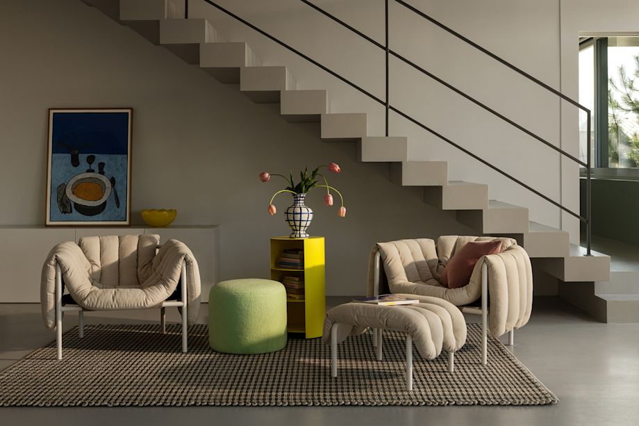 Lifestyle image of a living room/lounge scene featuring Puffy Lounge Chair + Ottoman, Bon Pouf, Hide Pedestal and Rope Rug.