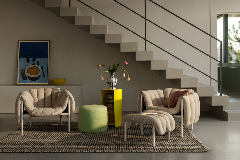 Lifestyle image of a living room/lounge scene featuring Puffy Lounge Chair + Ottoman, Bon Pouf, Hide Pedestal and Rope Rug.