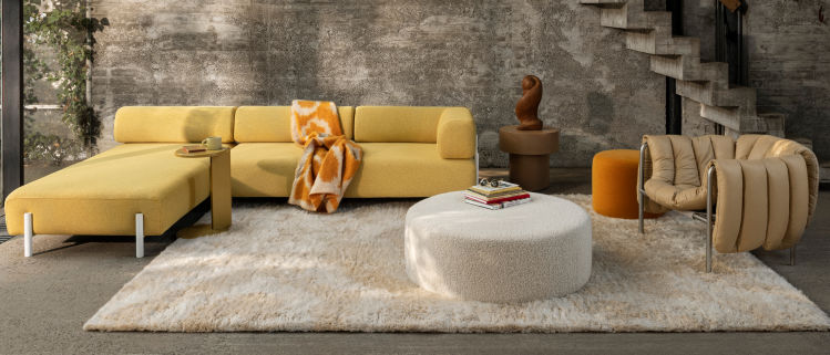 Hem - A living room scene featuring Palo Modular Corner Soft Left Sunflower, Lolly Side Table Ochre Yellow, Monster Throw Ochre / Off-White Ring, Monster Rug Beige / Off-White, Bon Pouf Round Large Eggshell, Stump Side Table Natural, and a Puffy Lounge Chair.