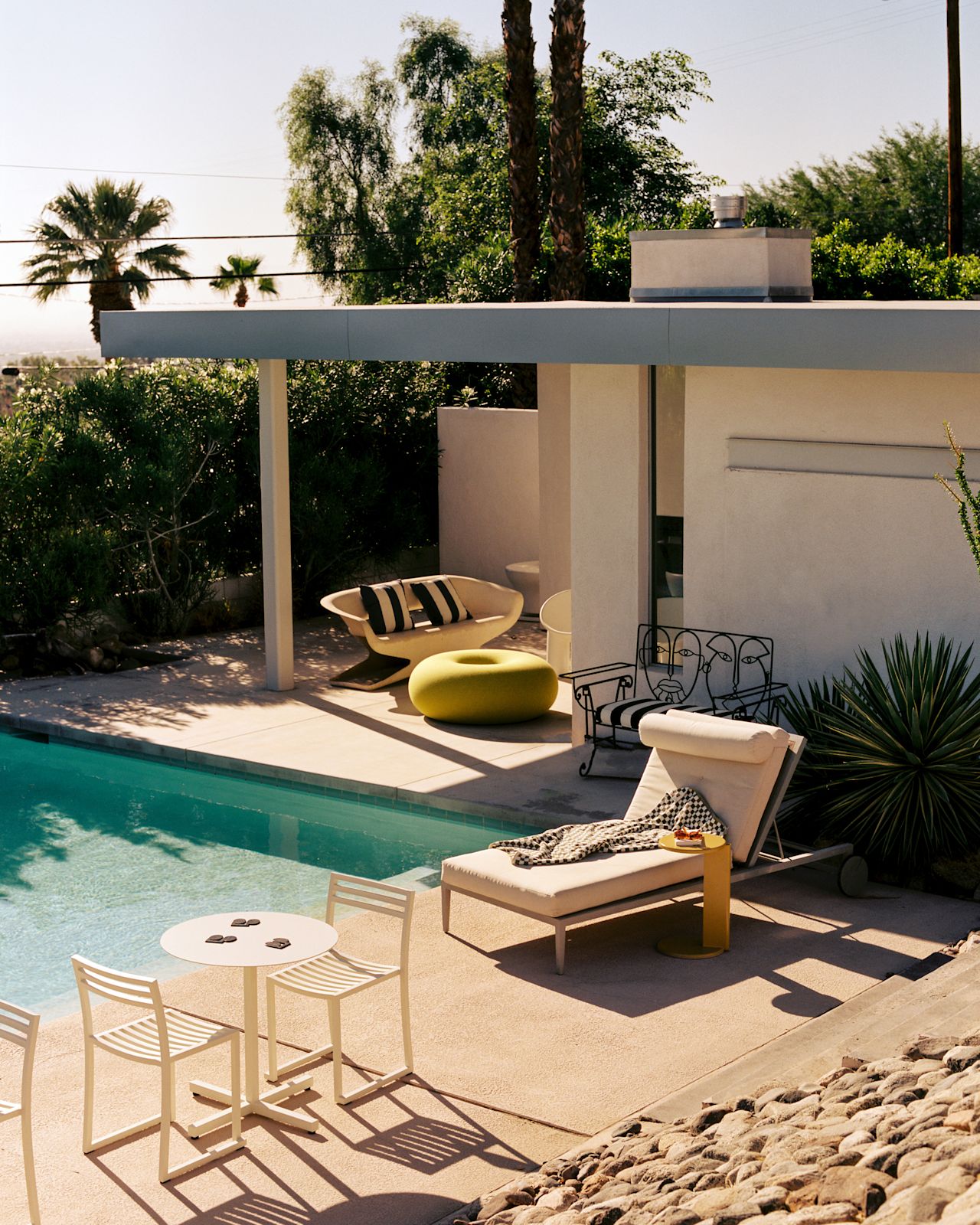 A lifestyle image of an outdoor patio scene featuring Boa Pouf, Lolly Side Table, Chop Chairs, Chop Table Round, and Disco Coasters.
