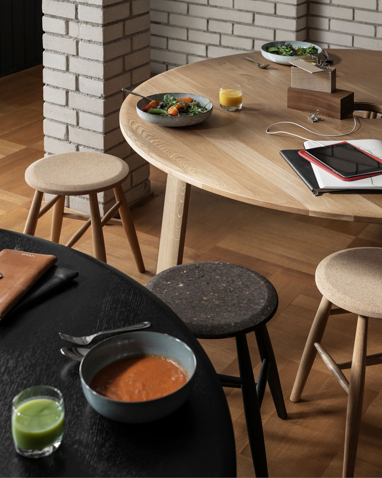 A lifestyle image of a dining scene featuring Alle Round Table and Drifted Stools.