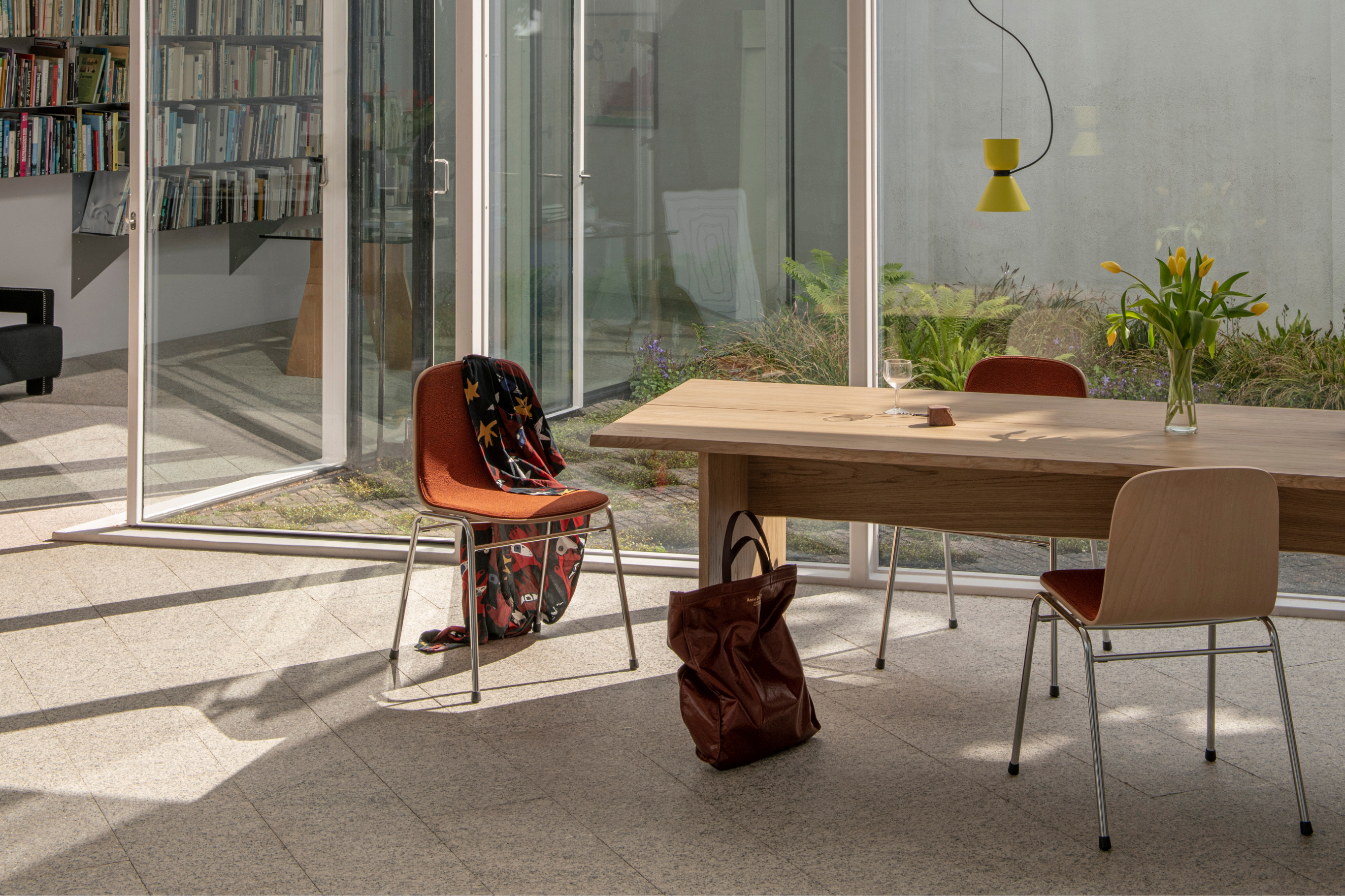 A lifestyle image of a dining scene featuring Bookmatch Table, Alphabeta Pendant Light, and Touchwood Chairs.