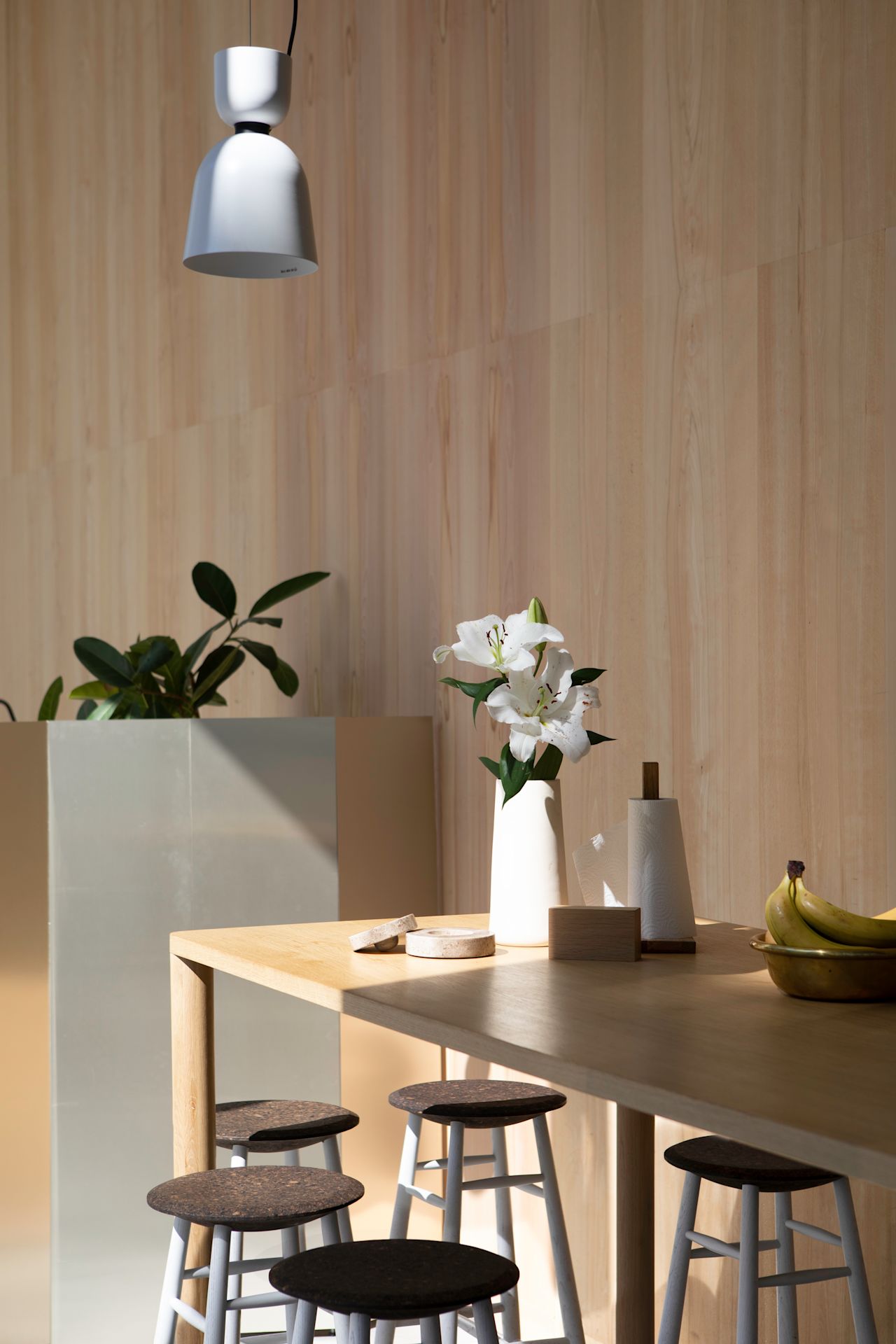 A lifestyle image of a dining scene from the Hem Headquarters in Stockholm, Sweden in 2018 featuring Drifted Bar Stools, Log Table and Alphabeta Pendant Light.