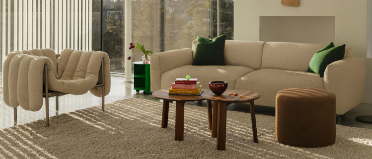 Hem - A living room scene featuring a Puffy Lounge Chair in Eggshell / Stainless Steel, Hide Side Table Pure Green, Koti 3-seater Sofa, Alle Coffee Tables Set of 2 Walnut, Bon Pouf Round Brown, and an Alphabeta Floor Lamp.