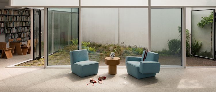 A lifestyle image of a lounge scene featuring Hunk Lounge Chair Icicle, Hunk Lounge Chair with Armrests Icicle, and Stump Side Table Natural.