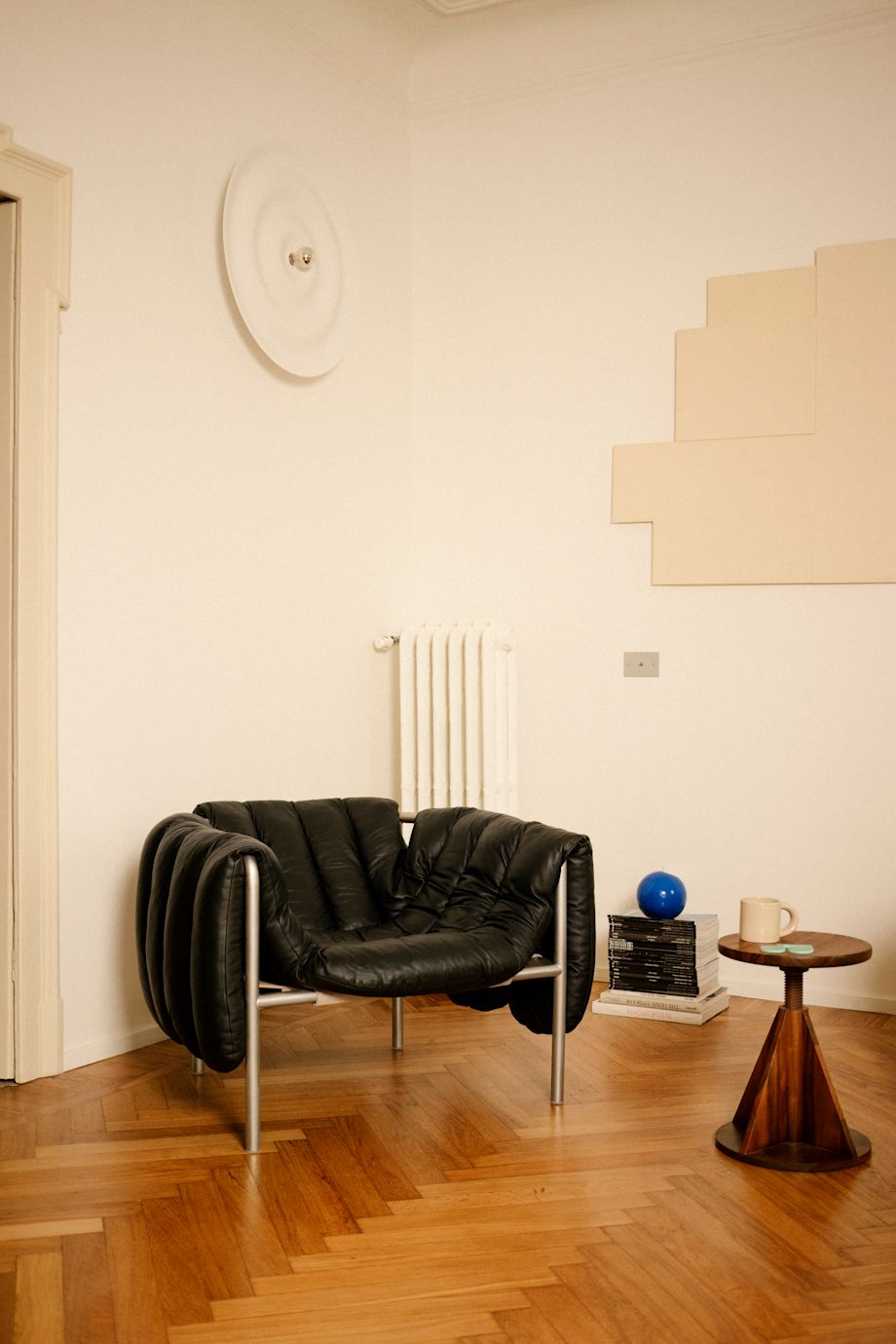 A lifestyle image of a lounge scene featuring All Wood Stool, Bronto Mug, and Puffy Lounge Chair.