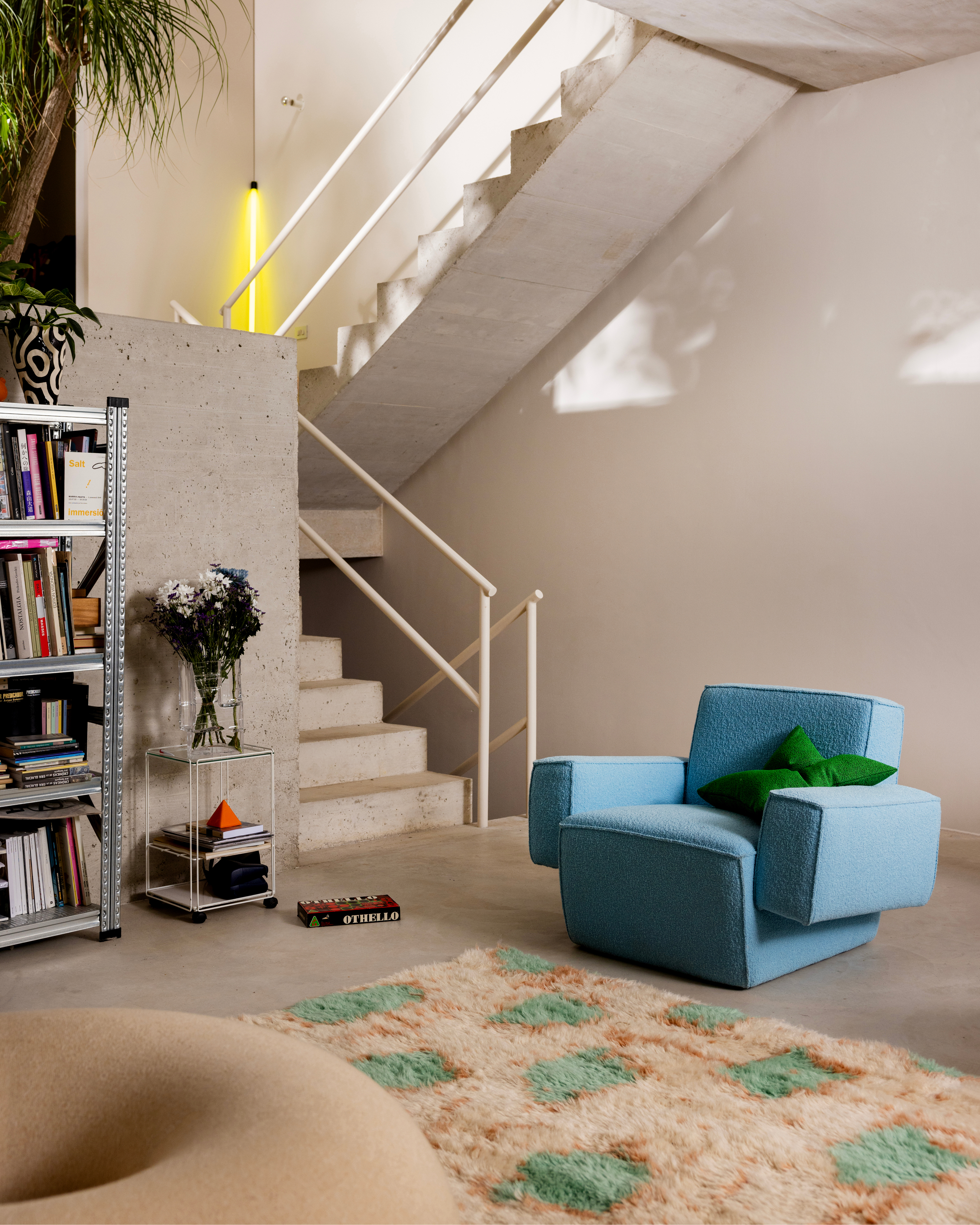 A lifestyle image of a lounge scene featuring Hunk Lounge Chair, Crepe Cushion, Monster Rug, Boa Pouf, and Brute Vase.