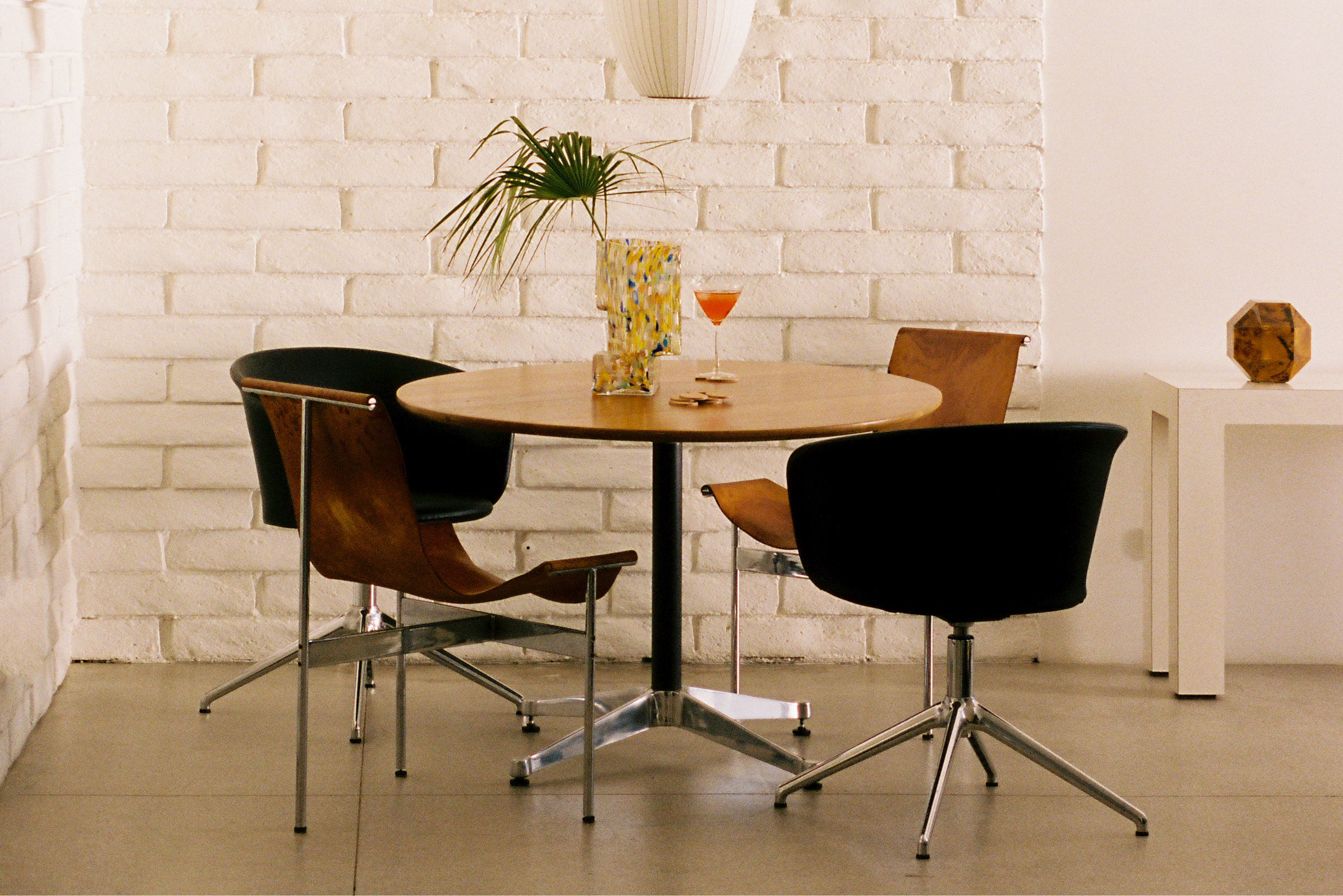 A lifestyle image of a dining scene featuring Kendo Swivel Chair, Disco Coasters, and Brute Vase.