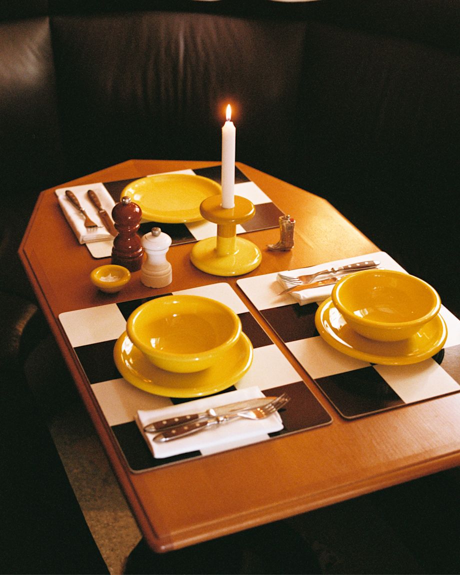 A lifestyle image of a dining scene featuring Bronto Bowls, Bronto Plates, Bronto Egg Cups, Check Placemats, and Pesa Candle Holders.