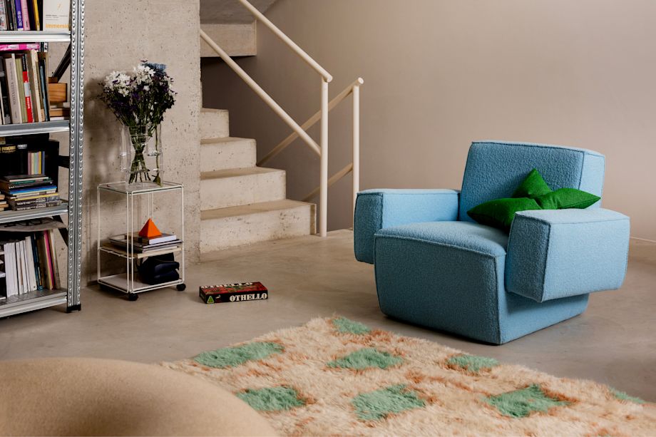 A lifestyle image of a lounge scene featuring Hunk Lounge Chair with Armrests, Crepe Cushion, Monster Rug, and Boa Pouf.