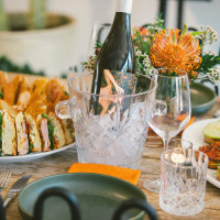 Beautifully set table with a bottle of Holly's Way in an ice bucket amidst bruschetta and sandwiches