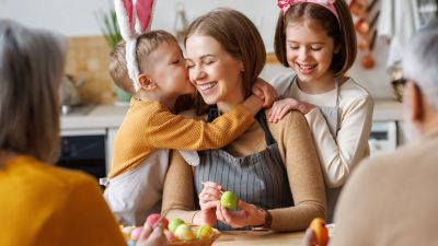 Moeder en kinderen die paaseieren schilderen