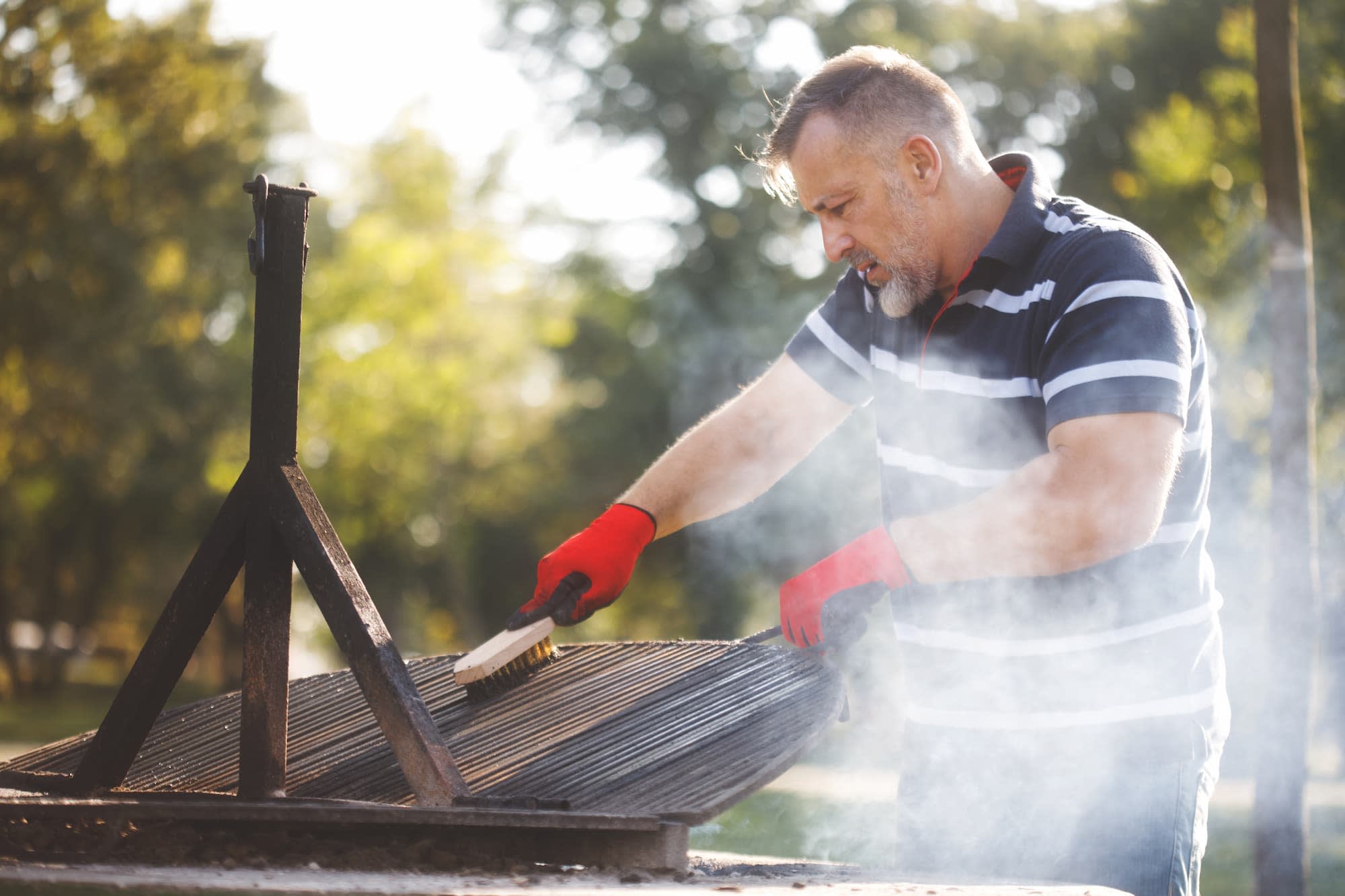 Un homme nettoie son barbecue – Aveve