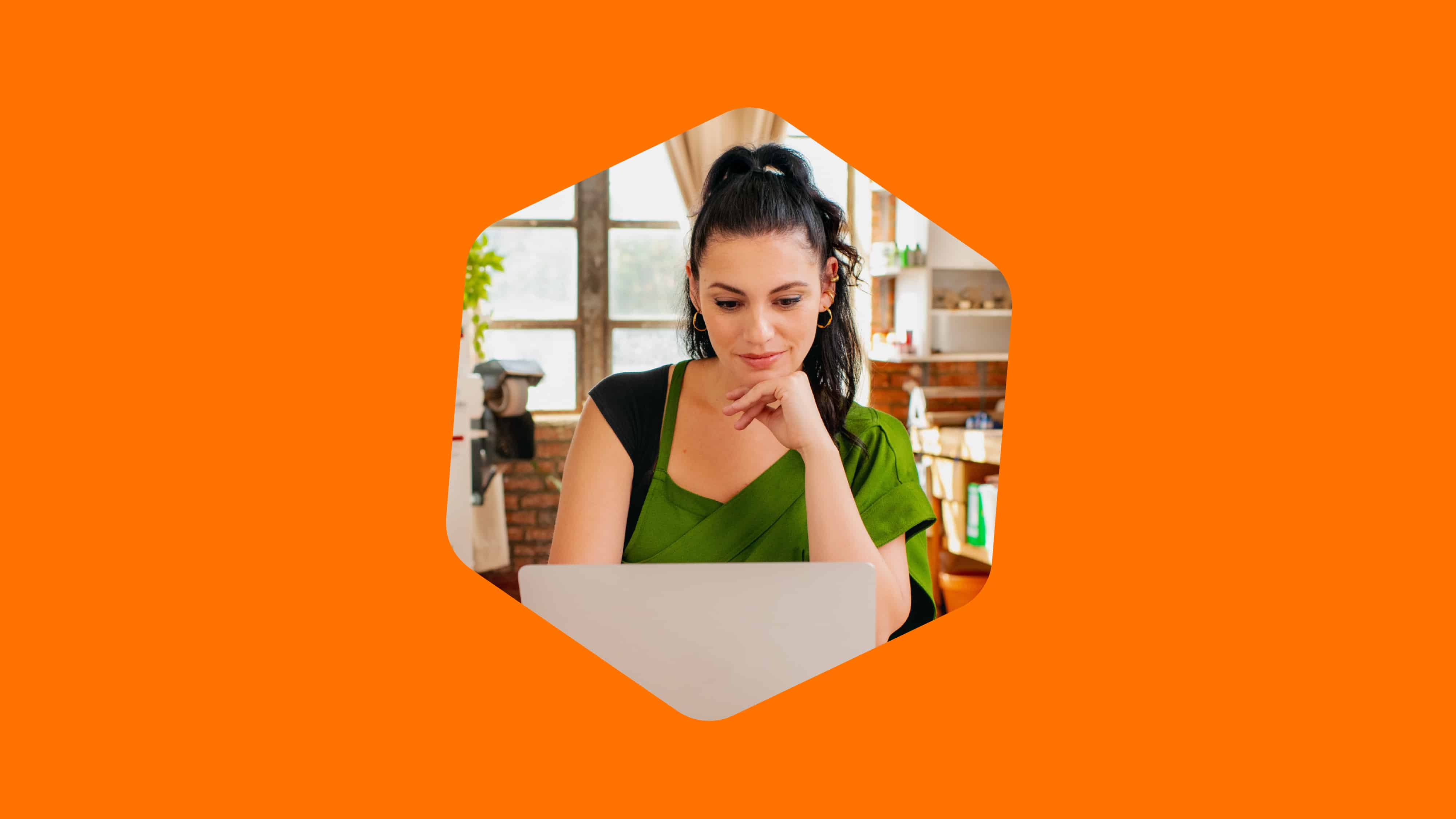 A woman in an green shirt is focused on her laptop, engaged in her work or browsing online.