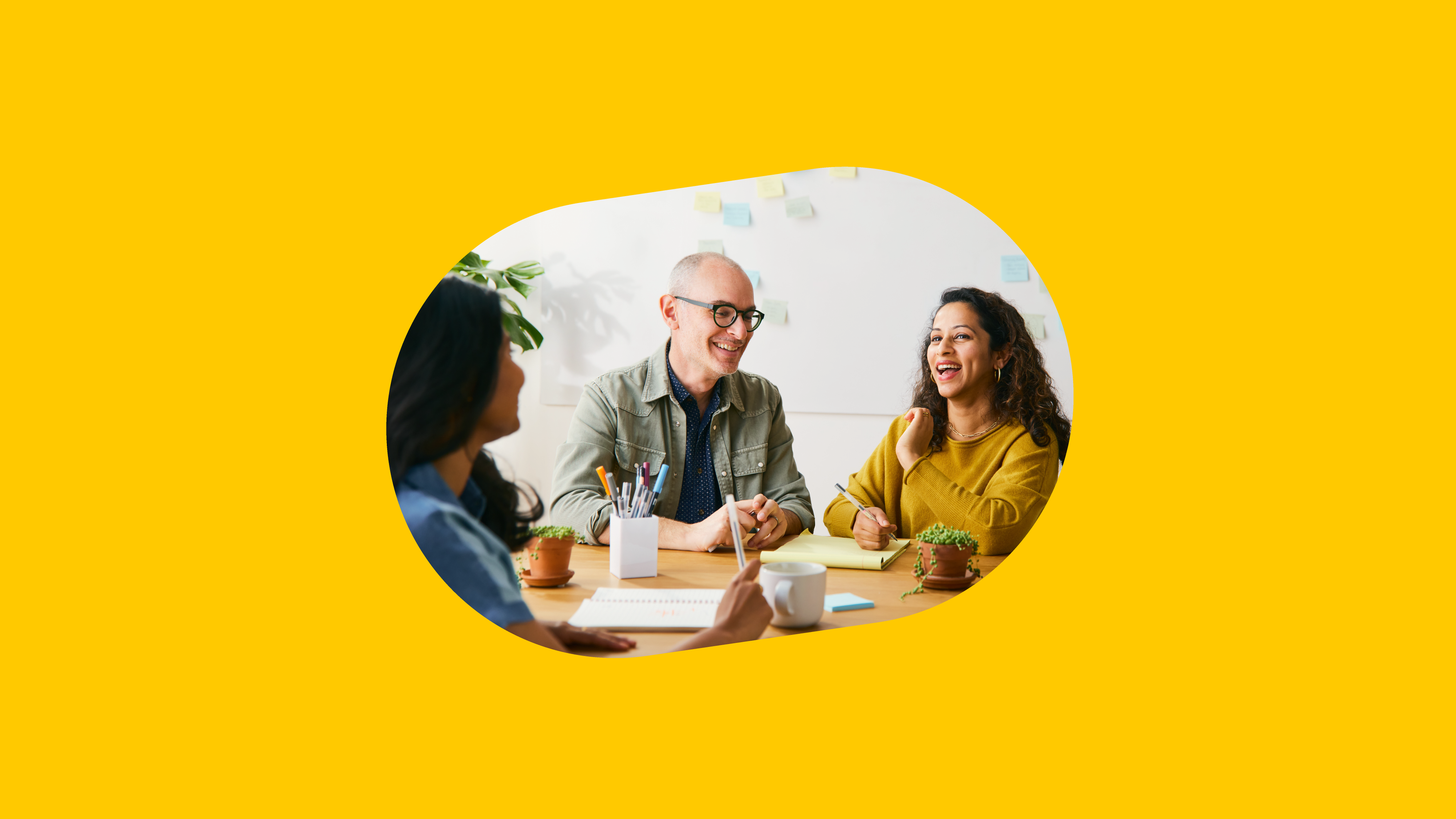Three people talking around a desk in an office