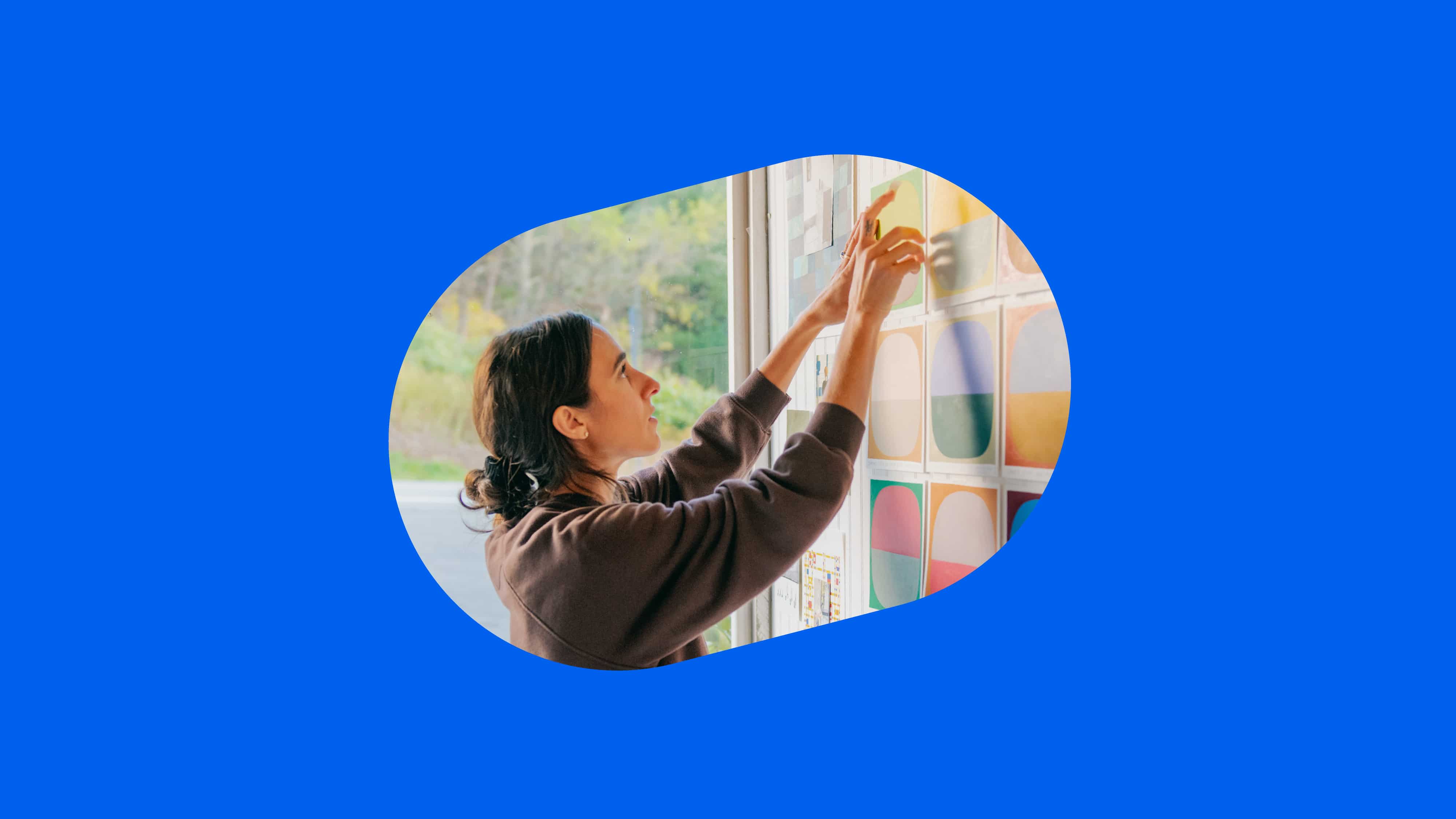 Woman arranging colorful swatches framed in an organic shape on a blue background