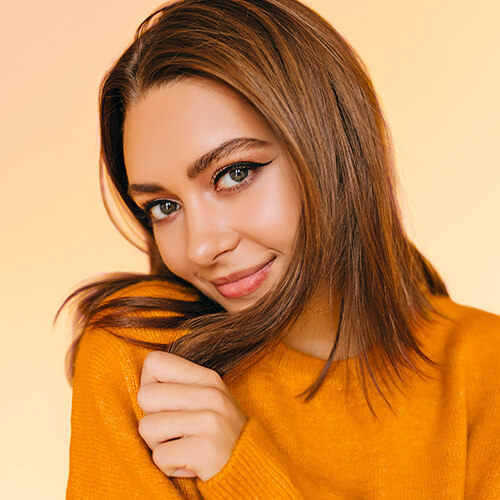 A smiling fair skinned model wearing a yellow sweater with straight thick hair | Waterless hair care