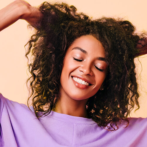 A smiling, medium skinned model with curly hair