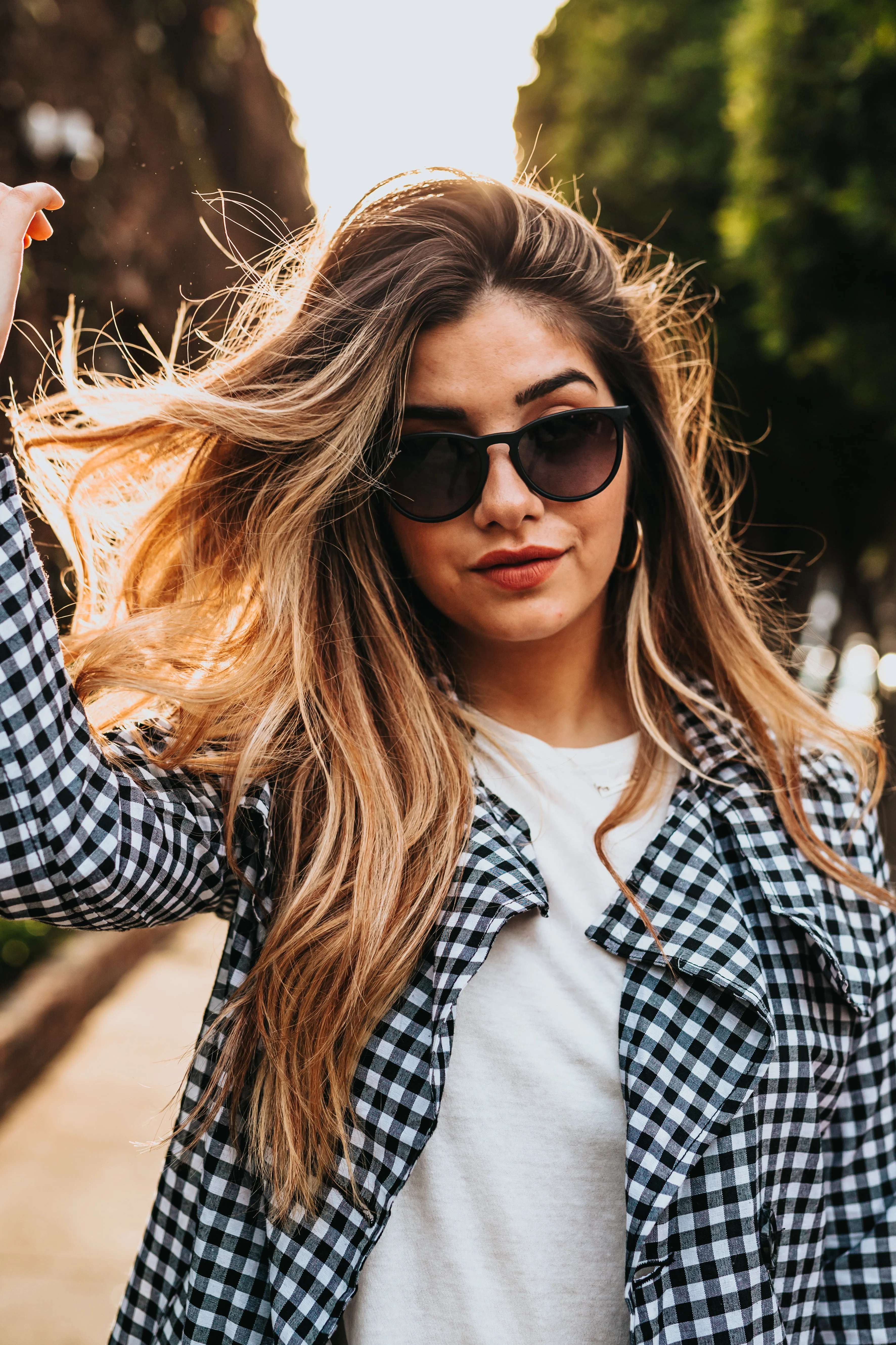 Outside photo of a woman with healthy brown hair wearing sunglasses