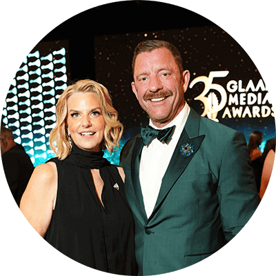 Brent Miller 身著綠色西裝外套，與 GLAAD 會長暨執行長 Kate Ellis 並肩站立，Kate Ellis 身穿黑色晚禮服。舞台背景顯示「35 GLAAD Media Awards」。