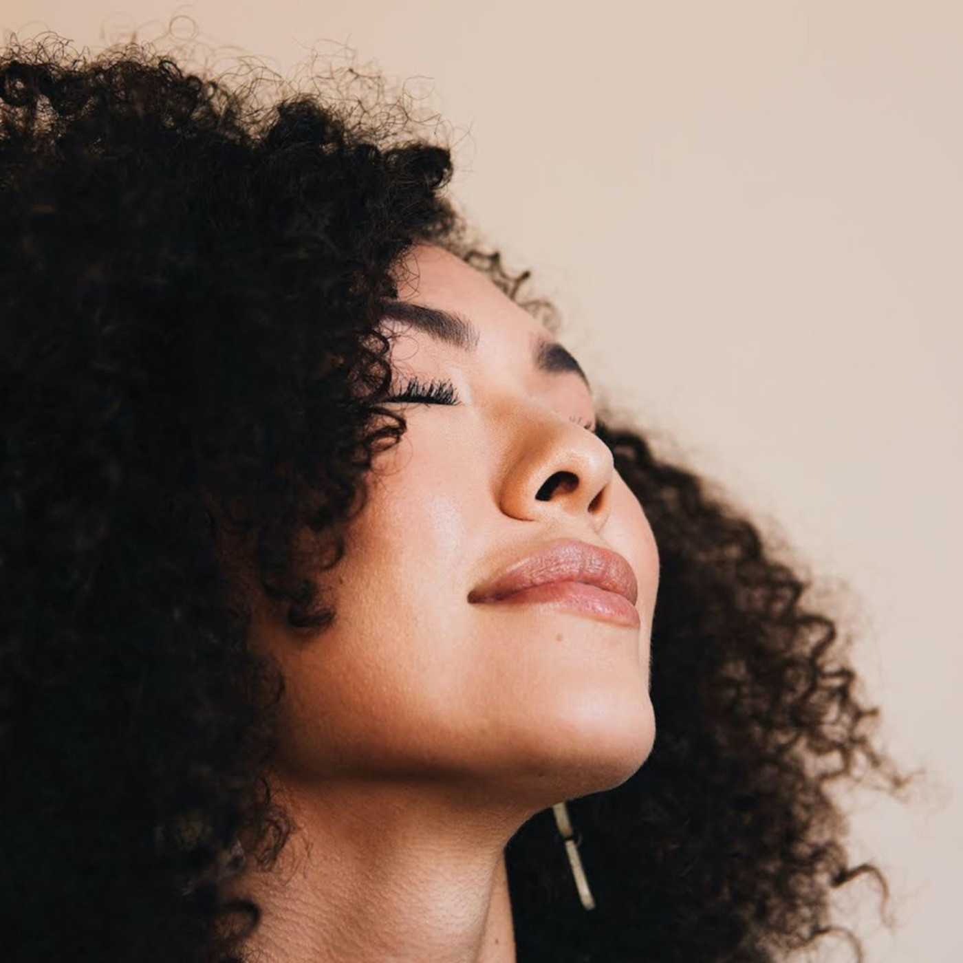 pink background with woman smiling to the side eyes closed