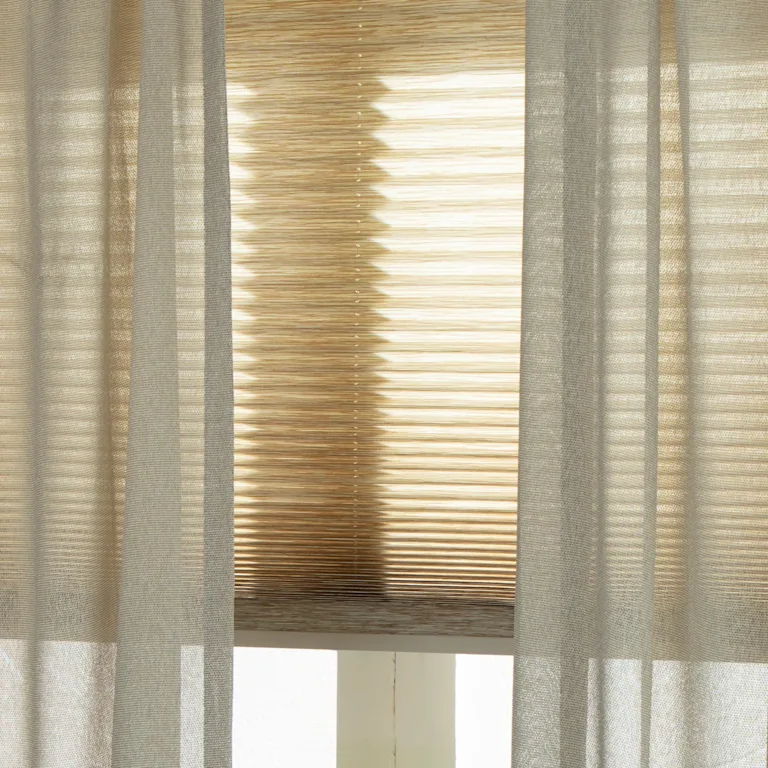 Beige inbetweens als aanvulling op lichte plisségordijnen voor het raam