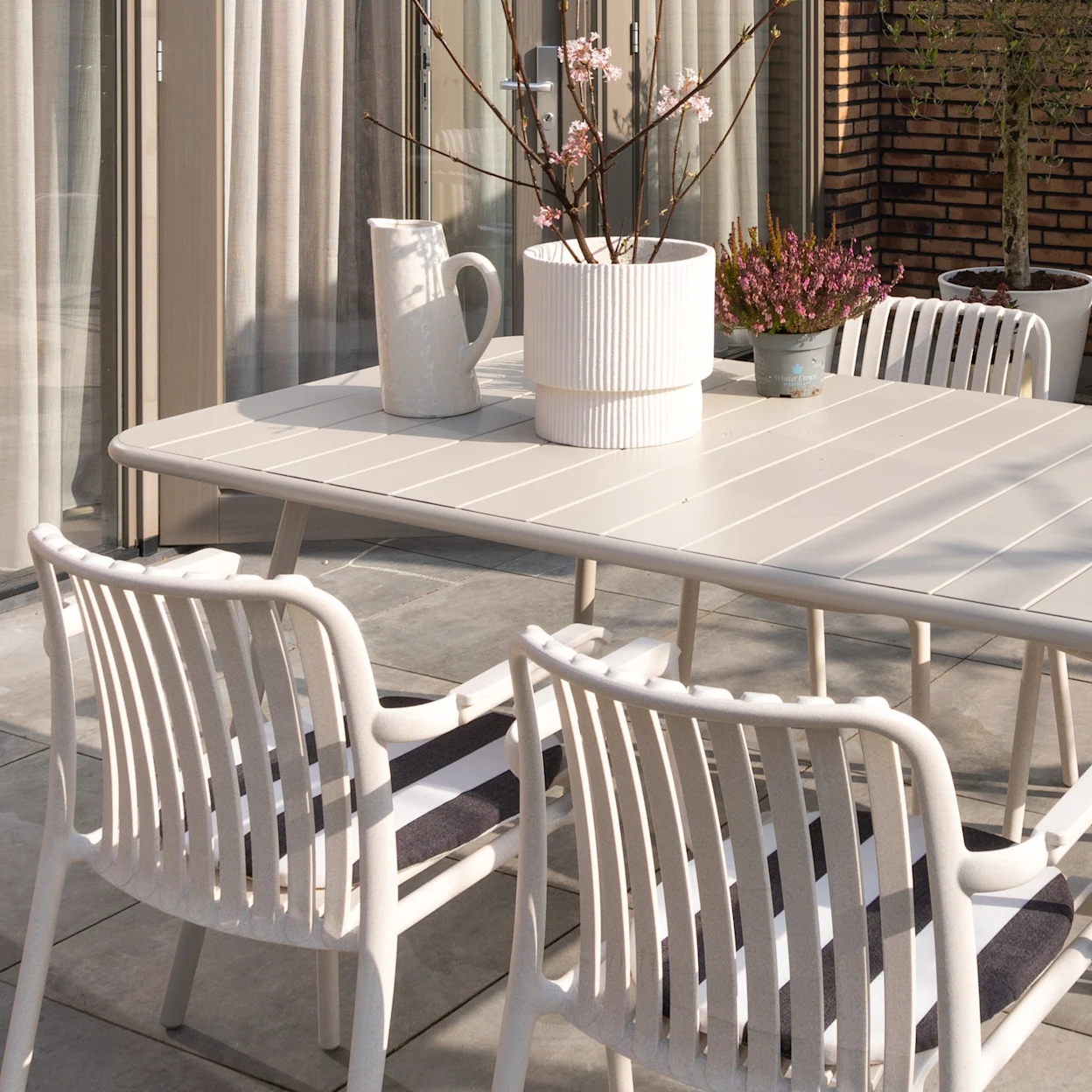 Beige tuinstoelen met een beige tuintafel