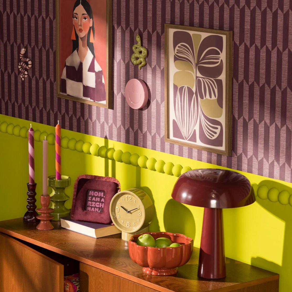 Retro sfeersetting met een bordeaux tafellamp en retro kandelaars, fotolijstjes en klokjes.