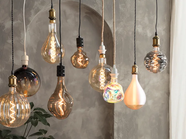 Diverse XL lichtbronnen hangen bij elkaar aan snoerpendels.