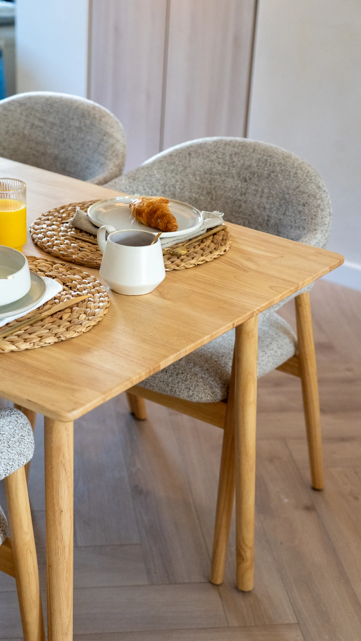 Landelijke eethoek met lichte houten tafel, grijze stoelen en aardewerk servies