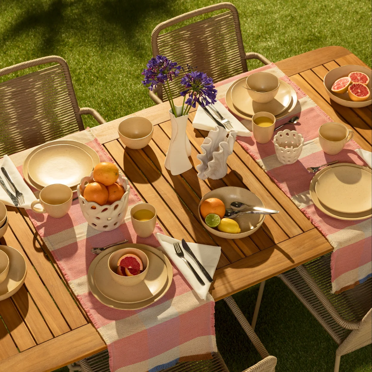 Een houten tuintafel met stoelen en buitenservies